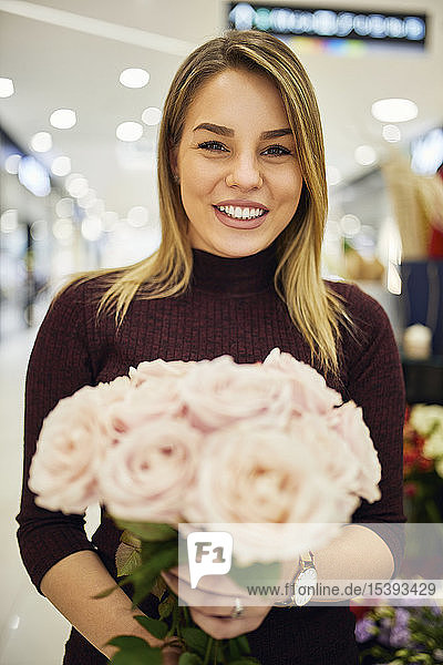 Porträt einer lächelnden Frau mit Blumenstrauss im Blumenladen