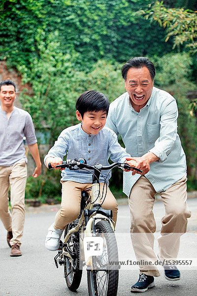 Grandpa to assist the grandson to ride a bicycle