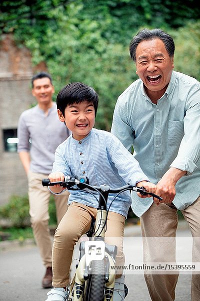 Grandpa to assist the grandson to ride a bicycle