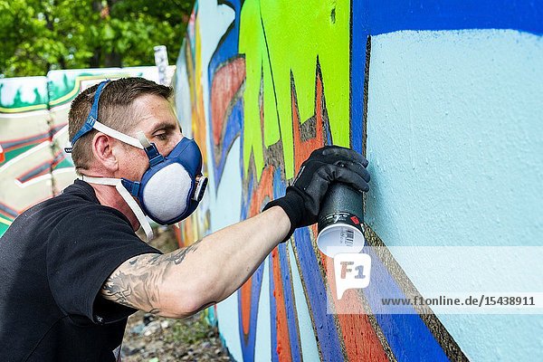 Berlin Germany. Graffity artist creating jet another piece of urban art on parts of the former Belin Wall bordering former East-Germany or DDR.