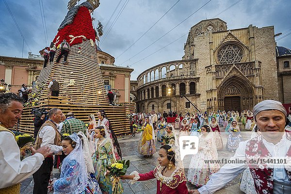 Fallas festival. Falleros and Falleras in traditional dress. Parade to the Plaza de la Virgin in order to make an offering of flowers to Our Lady of the Forsaken the Patron Saint of Valencia. The celebration takes place from 4 pm until past nightfall. With all of the bunches of flowers given by the falleras to the Virgin an impressive 15 metre-high tapestry is formed on the main façade of the Basilica and a mantle is made for the Virgin. Valencia. Valencian Community. Spain.