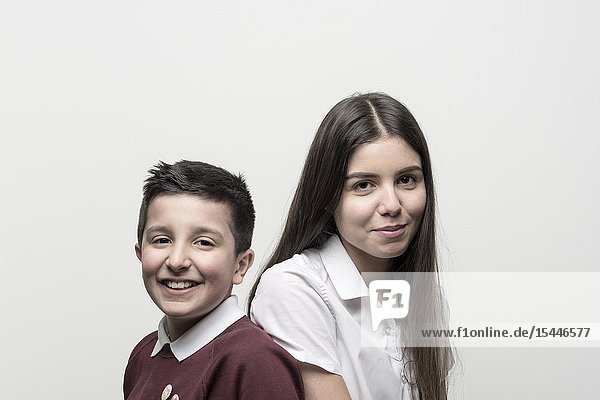 UK England Portrait of 10 years old boy and his teenage sister both in school unoforms. Studio settings.
