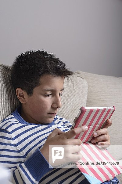 Young boy plays games on computer tablet.