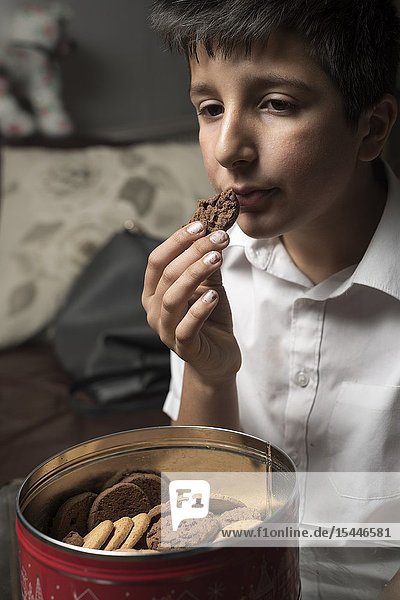Boy 11 years old eats chocolate cookie.