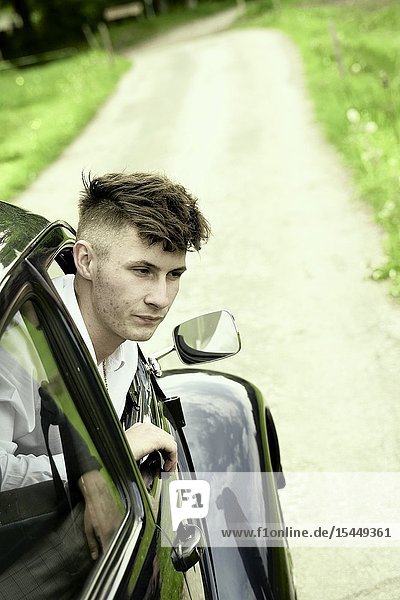 Young man looking out of vintage car at countryside in Bad Tölz Germany