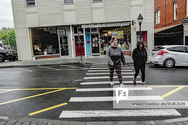 New Milford Connecticut USA Two women cross the street in the downtown.