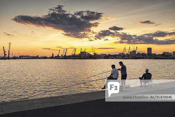 Anglers against the setting sun in the Port of Burgas Bourgas Bulgaria.