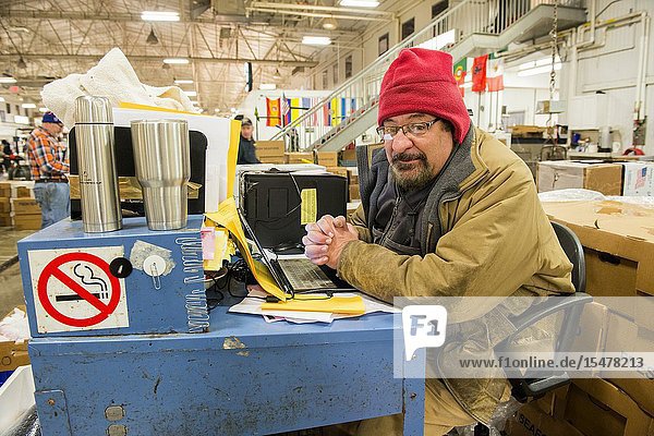 New York City USA. Wholesale market stall employee waiting to crunch numbers after preparing orders for customers at the New Fulton Fish Market Hunts Point The Bronx.