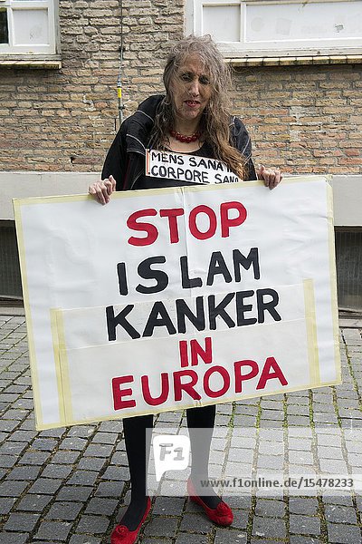 Breda Netherlands. Female Pegida supporter with sign protesting during a local rally and demonstration. Pegida is a patriotic political organization opposing to immigration of Islamic & Muslim people into the Christian Western-European Culture.