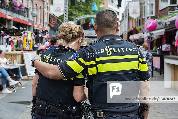 Tilburg Netherlands. Male Policeman giving his female colleague a friendly arm when patrolling the annual fair's terrain.