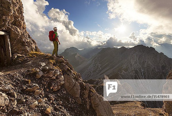 A hiker observes the panorama outside a war cave along the Bepi Zac High Trail Costabella Ridge Marmolada group Dolomites Moena Fassa Valley Trento province Trentino-Alto Adige Italy.