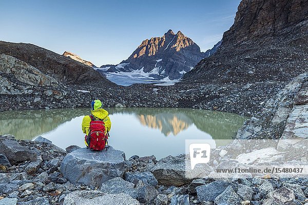 Hiker looks at Piz Roseg from the epiglacial lake next to Fellaria Glacier Malenco Valley Sondrio Province Valtellina Lombardy Italy.