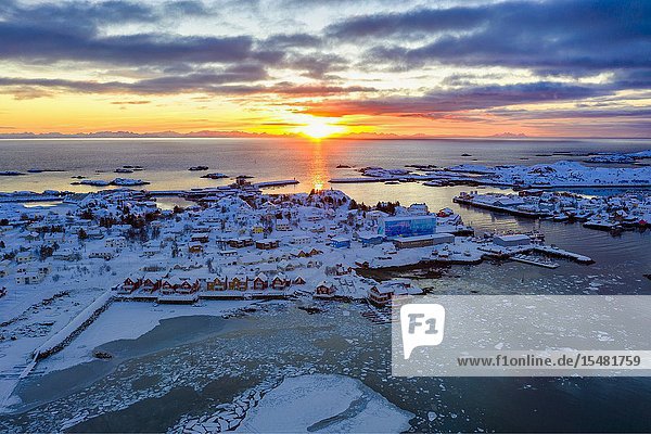 Aerial panoramic of the rising sun over Ballstad and icy sea Vestvagoy Lofoten Islands Norway.