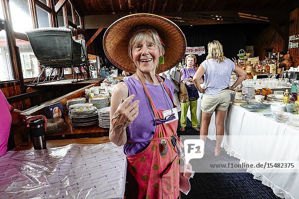 Cornwall Connecticut USA A senior woman volunteer at an annual rummage or tag sale sale in the community wearing a new hat she bought for one dollar.