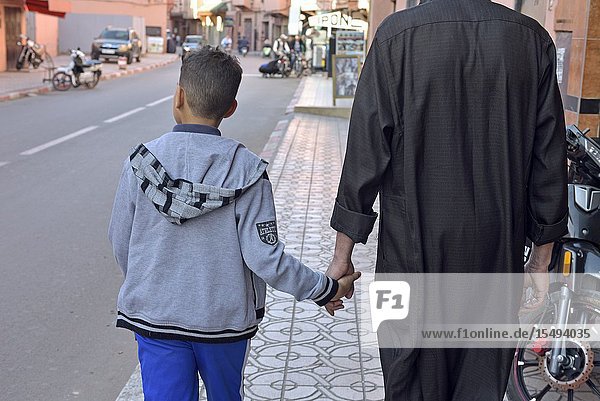 Father and son walking in a street Medina of Marrakech Morocco North West Africa.