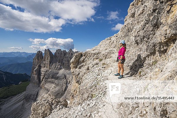 Young woman standing on the via ferrata that leads to the summit of Mount Paterno in summer. Sesto Dolomites Trentino Alto Adige Italy.