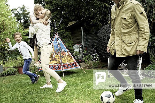 Family playing soccer in garden
