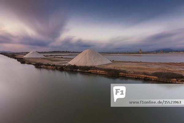 Salt pans with rows of tanks and two fully functional windmills on the coast connecting Marsala to Trapani Trapani province Sicily Italy.