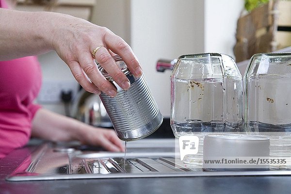 Woman washing out jars and tins for recycling