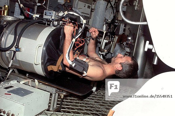 Scientist-astronaut Owen K. Garriott science pilot of the Skylab 3 mission lies in the Lower Body Negative Pressure Device in the work and experiments area of the Orbital Workshop (OWS) crew quarters of the Skylab space station cluster in Earth orbit. This picture was taken with a hand-held 35mm Nikon camera. Astronauts Garriott Alan L. Bean and Jack R. Lousma remained with the Skylab space station in orbit for 59 days conducting numerous medical scientific and technological experiments. The LBNPD (MO92) Experiment is to provide information concerning the time course of cardiovascular adaptation during flight and to provide in-flight data for predicting the degree of orthostatic intolerance and impairment of physical capacity to be expected upon return to Earth environment. The bicycle ergometer is in the right foreground.