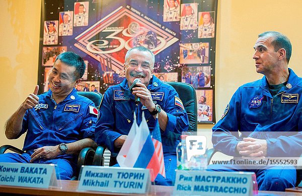 Expedition 38 Soyuz Commander Mikhail Tyurin of Roscosmos center talks as Flight Engineer Koichi Wakata of the Japan Aerospace Exploration Agency left and Flight Engineer Rick Mastracchio of NASA listen while quarantine behind glass during the final press conference held a day ahead of their launch to the International Space Station Nov. 6 2013 at the Cosmonaut Hotel in Baikonur Kazakhstan.