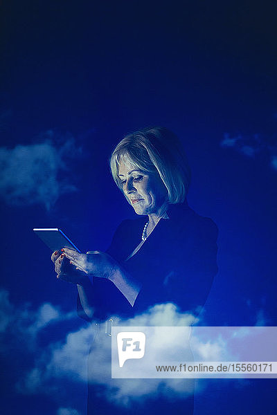 Doppelbelichtung Geschäftsfrau mit digitalen Tablet gegen blauen Himmel mit Wolken