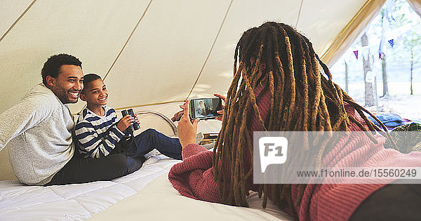 Frau mit Fotohandy fotografiert Ehemann und Sohn in Camping-Jurte