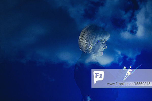 Doppelbelichtung Geschäftsfrau mit digitalen Tablette gegen blauen Himmel mit Wolken