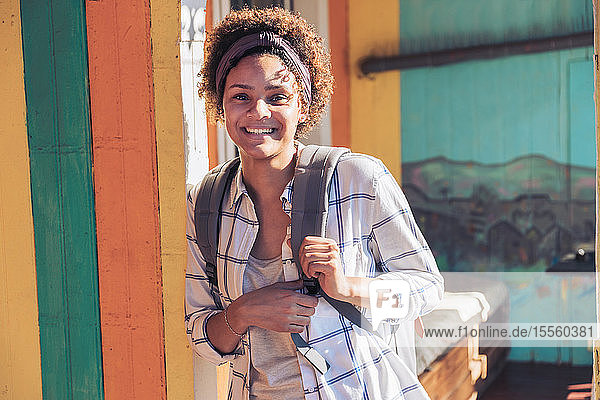 Porträt lächelnde  selbstbewusste junge Frau auf sonniger Veranda