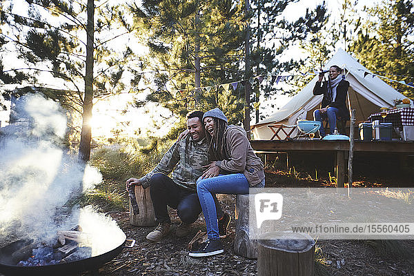 Glückliches Paar am Lagerfeuer auf dem Campingplatz im Wald