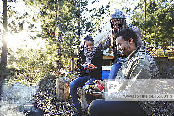 Glückliche Freunde beim Essen auf dem sonnigen Campingplatz