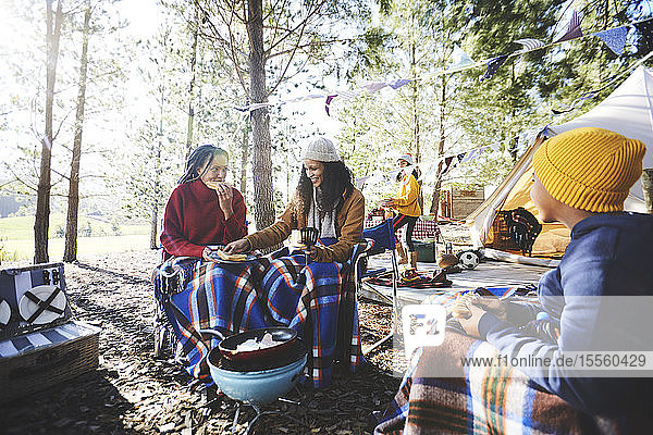 Lesbisches Paar und Kinder essen auf einem sonnigen Campingplatz