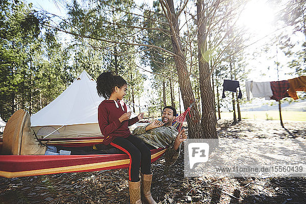 Vater und Tochter in der Hängematte auf einem sonnigen Campingplatz im Wald