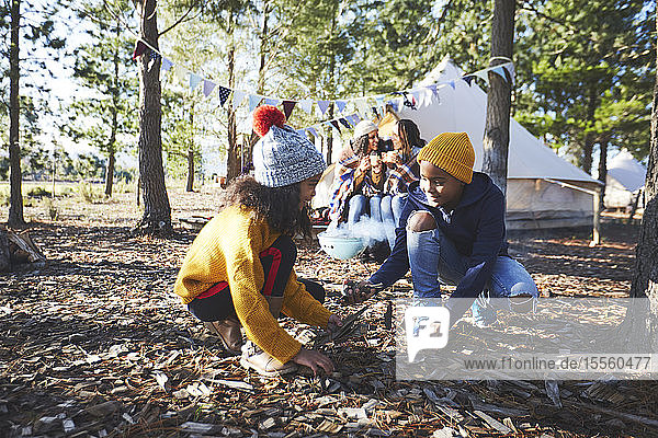 Bruder und Schwester sammeln Brennholz auf einem Campingplatz im Wald