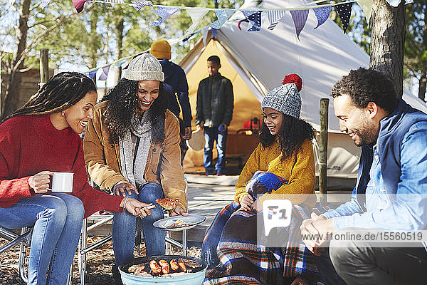 Glückliche Freunde und Familie beim Kochen am Lagerfeuer auf dem Campingplatz