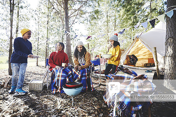 Lesbisches Paar und Kinder beim Grillen auf dem Campingplatz im sonnigen Wald