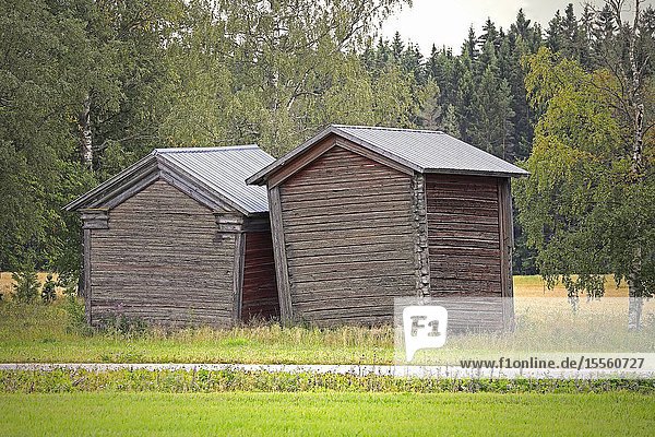 Two small  leaning granaries or barns in Finnish countryside. Jalasjärvi  Osthrobotnia  Finland. HDR  light filtering..Black and white  light filtering.