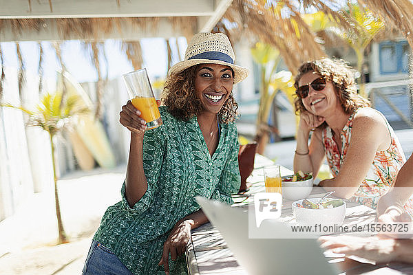 Porträt einer glücklichen Frau  die einen Cocktail an einer sonnigen Strandbar trinkt