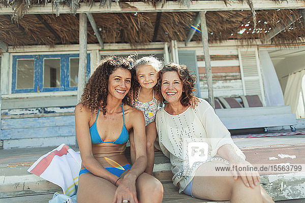 Portrait happy multi-generation women outside sunny beach hut