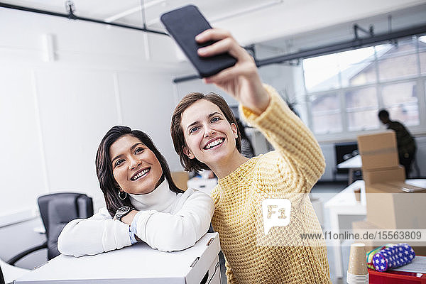 Lächelnde Geschäftsfrauen machen ein Selfie im neuen Büro