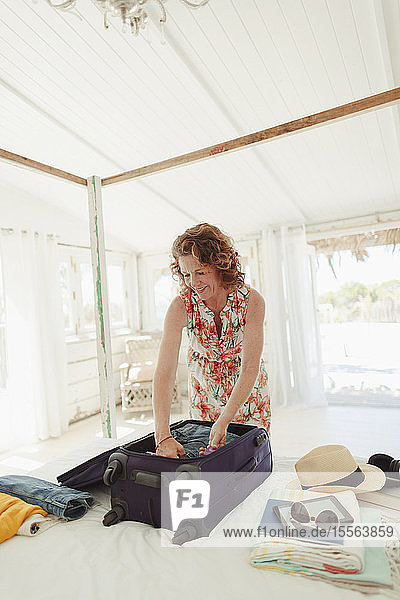 Frau beim Auspacken des Koffers im Schlafzimmer einer Strandhütte