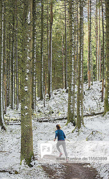 Frau joggt im verschneiten Wald