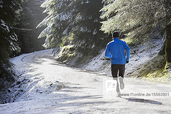Mann joggt im verschneiten Wald