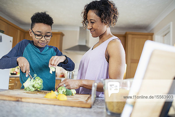Mother and son cooking  cutting vegetables in kitchen