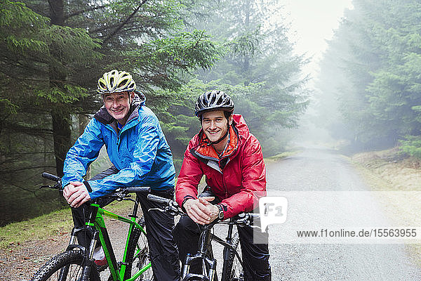 Portrait father and son mountain biking in rain