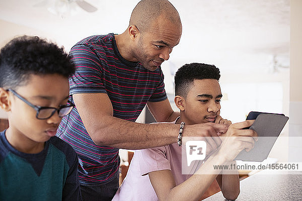 Vater und Sohn im Teenageralter benutzen ein digitales Tablet