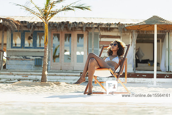 Gelassene junge Frau im Bikini beim Sonnenbaden am sonnigen Strand