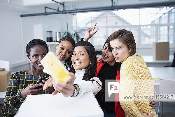 Happy businesswomen moving into new office  taking selfie