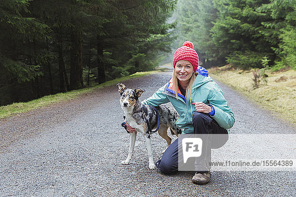 Porträt Frau beim Wandern mit Hund im Wald