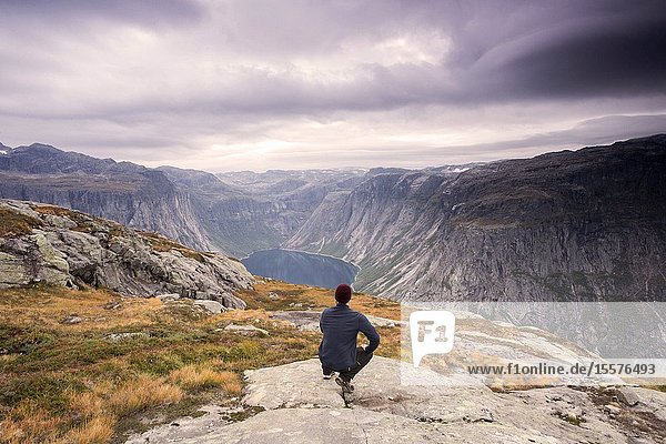 Hiker is standing on a mountain top and watching over a calm lake Beautiful moment miracle of nature. Hiker silhouette watching. Person standing nature.